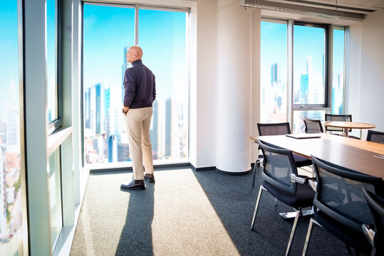 Businessman looking out city from a large window in the office