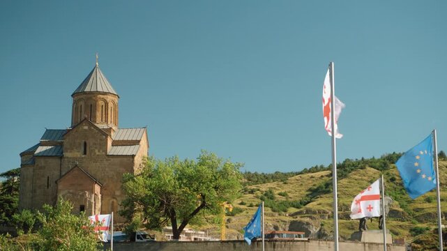 Metekhi Church with waving Georgian and European Union flags