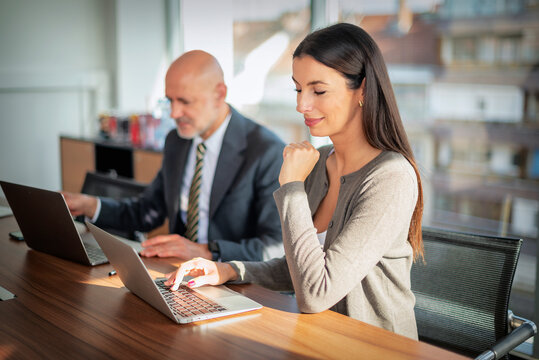 Two mid-aged business people working together on a laptop in a modern office