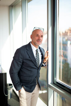 Mid-aged businessman contemplating in a modern bright office with a view of the city