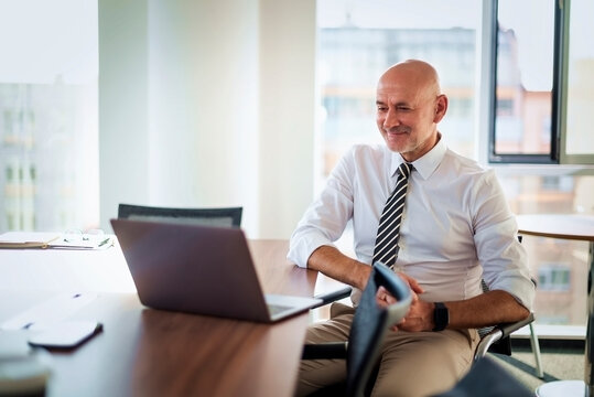 Smiling man with laptop having a video call in a bright office