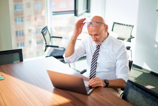 Smiling man with laptop having a video call in a bright office