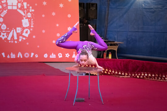 Young gymanst balances on a stage table. Concept: Christmas holiday campaign ads, festive family entertainment, and youth talent promotions