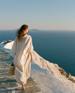 Elegant Woman Walking Alone on Quiet Greek Island Coastal Path in Morning Sun
