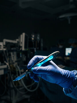 Surgeon Holding Illuminated Smart Scalpel in Dark Operating Room