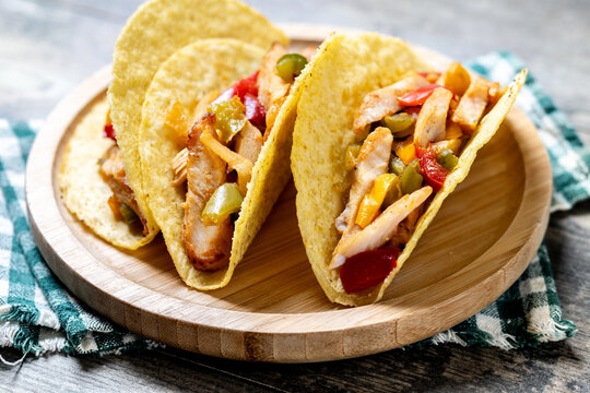 Mexican chicken tacos with bell peppers and onions on wooden table