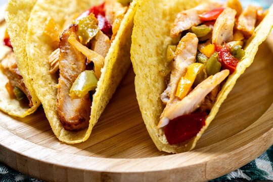 Mexican chicken tacos with bell peppers and onions on wooden table. Close up