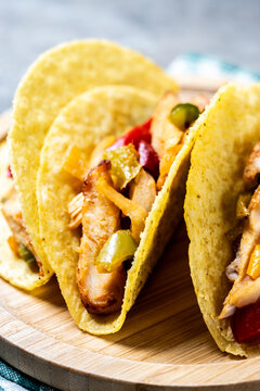 Mexican chicken tacos with bell peppers and onions on wooden table. Close up