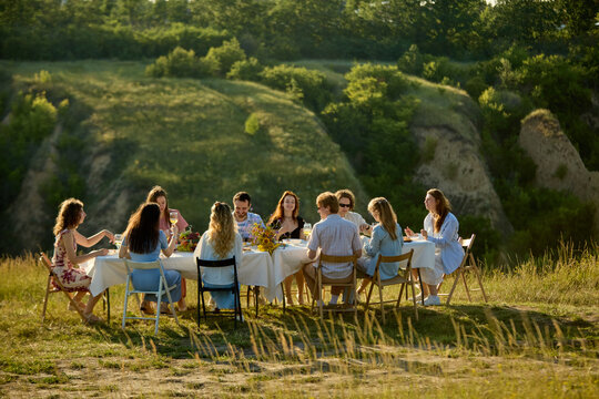 Large group of friends sharing alfresco meal at scenic Riviera retreat. Concept of destination dining, community connection, Mediterranean tourism.