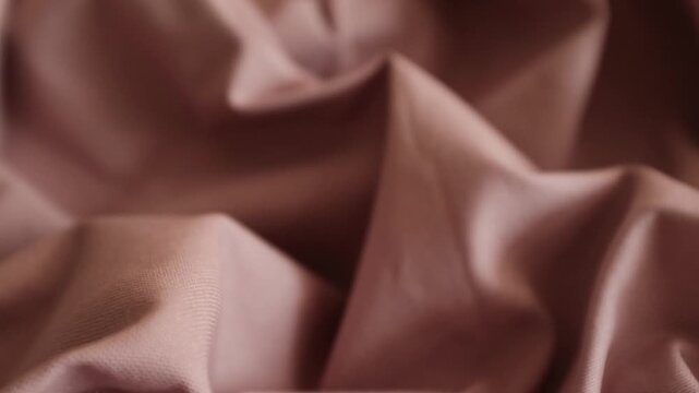 Dusty rose fabric shifting slowly, displaying its crumpled texture and soft, natural folds. Perfect for fashion branding campaigns, textile promotional videos, motion backgrounds, or interior design