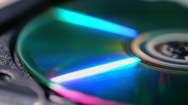 Macro view of a compact disc center reflecting green, blue and red light across its glossy surface. Concept retro technology, data storage, music branding and digital advertising.