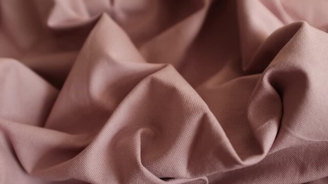 Dusty rose fabric shifting slowly, displaying its crumpled texture and soft, natural folds. Perfect for fashion branding campaigns, textile promotional videos, motion backgrounds, or interior design