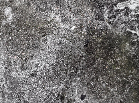 Dark grey and white Concrete Ground with wet stains, mineral grains, scattered Pebbles and rough worn Surface. Abstract distressed grunge Texture Background with damp rocky pattern, closeup.