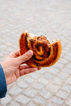 a man holding a bitten danish kanelsnegl