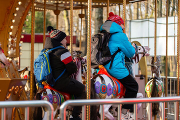 Children ride on a carousel at an amusement park during a winter afternoon in a city location © Светлана Лазаренко