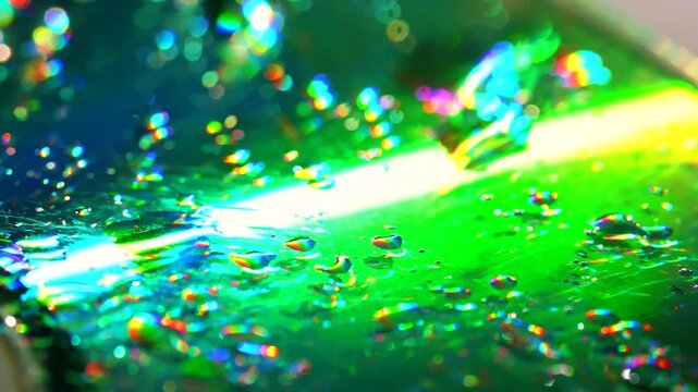Water droplets cover a compact disc reflecting vivid rainbow light in a macro. Concept retro technology, abstract backgrounds, music branding and digital advertising.