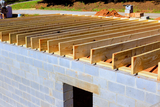 Workers place wooden beams trusses on top of block structure during construction project