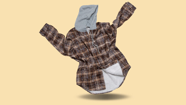 Floating men brown check flannel shirt with grey hood levitating over beige background. Warm fleece lined plaid shacket floating in mid air with drop shadow