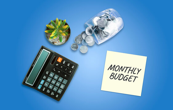 Flat lay monthly budget note with calculator coins and blue background