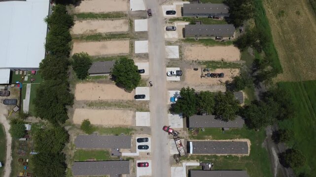 FM 306 area commercial yards border dense manufactured housing developments. Vertical aerial shot highlights internal street network connecting individual homes, New Braunfels, TX