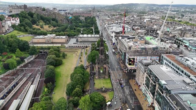 Aerial orbit view around the iconic Scott Monument in Edinburgh, showing Princes Street Gardens, National Gallery, Edinburgh Castle, and city traffic, 4k drone footage