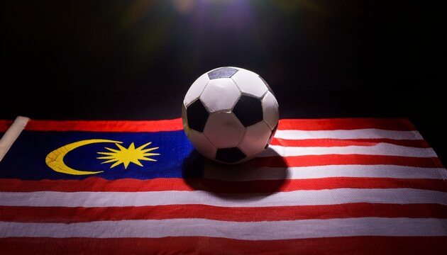 light shining on soccer ball placing on malaysia flag in dark room