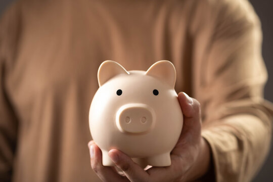 Close-up of a hand holding a piggy bank, symbolizing saving money, financial planning, personal finance, budgeting, wealth management, investment growth, and long-term financial security.