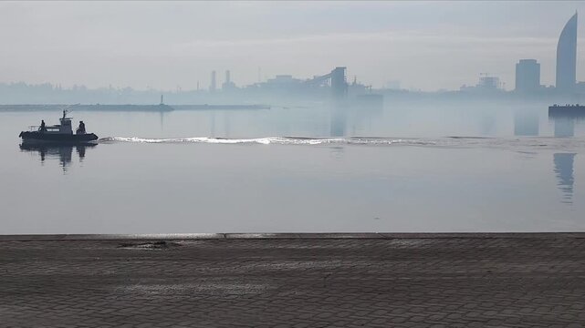 Small ship crossing the river at port of montevideo city during a misty winter morning in Montevideo.