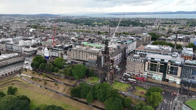 High angle aerial shot of Scott Monument and Princes Street in Edinburgh, extending towards the Firth of Forth sea and coastal horizon, 4k drone footage