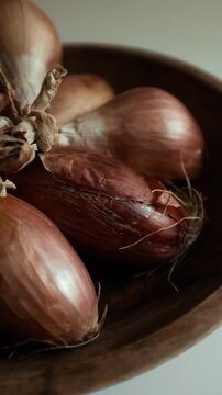 Whole echalion banana shallots with dry, papery peel rests tied together on a white grid-patterned kitchen linen. For cooking shows, culinary blogs, recipe tutorials, organic farming promotions.