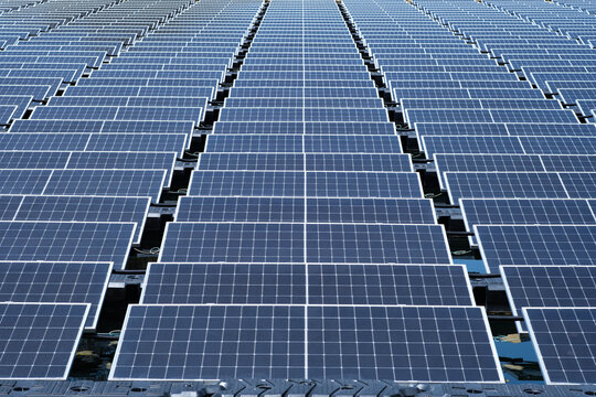 Large floating solar farm with photovoltaic panels arranged in geometric rows across a water reservoir. Clean renewable energy, sustainable electricity generation, green technology and infrastructure.
