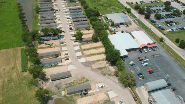 Windgate Park neighborhood boundaries meet commercial facilities near local transit arteries. High aerial vantage displays parallel residential lots adjoining business parking, New Braunfels, TX