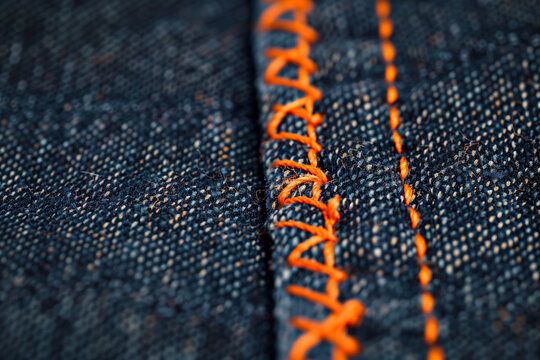 Blue denim fabric with orange stitches texture background