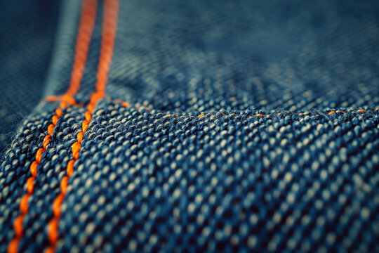 Blue denim fabric with orange stitches texture background