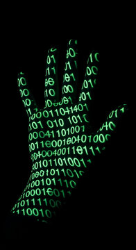 Green binary code projected onto a hand against a black background, symbolizing digital information, technology, and data.