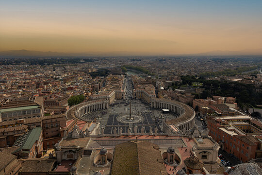 Warm sunset light bathes the majestic colonnades of Saint Peters Square and the sprawling Rome skyline. Such breathtaking ancient panoramas inspire spiritual journeys and memorable European vacations.