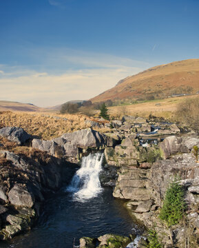 Sunlit waterfall cascades over mossy rocks