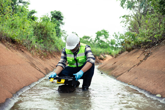 Water quality inspection in agricultural irrigation canal by environmental engineer collecting water samples.