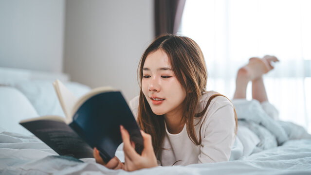 Asian woman solitude living in home apartment reading a book study lying in bedroom