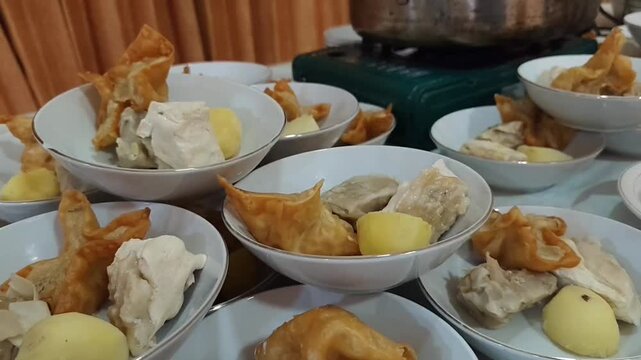 Close-up video of traditional Indonesian Batagor ingredients arranged in serving bowls before serving. The footage features fried tofu, fish dumplings, fried wontons, and other authentic ingredients, 