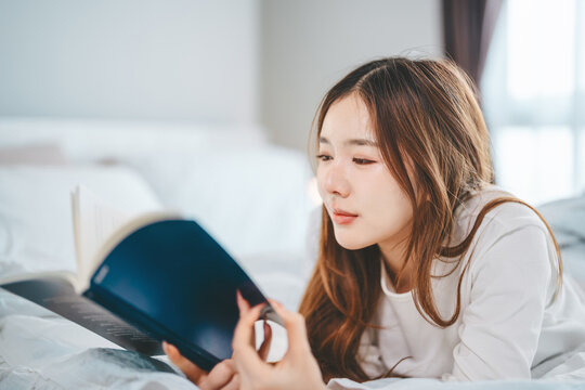 Asian woman solitude living in home apartment reading a book study lying in bedroom