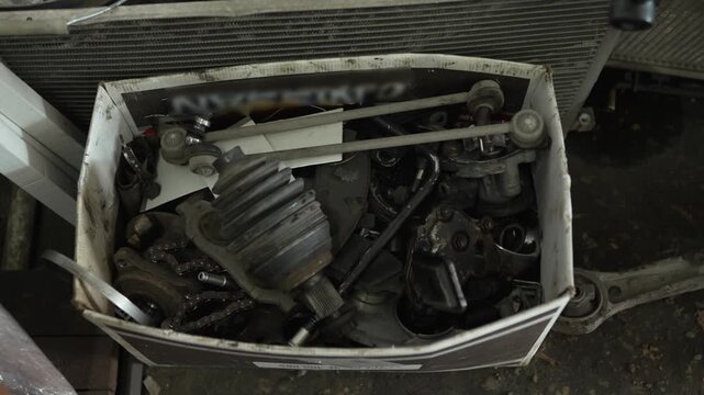 A cardboard box is filled with various used car parts.