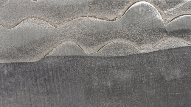 Macro texture of a damascus steel knife blade with a wavy pattern.