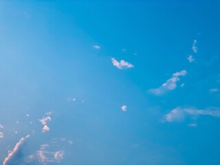 Clean blue sky with delicate cloud formations and gentle sunlight. An atmospheric natural background ideal for environmental themes, wellness concepts, travel content, and creative design layouts. © Arlina Elsiska