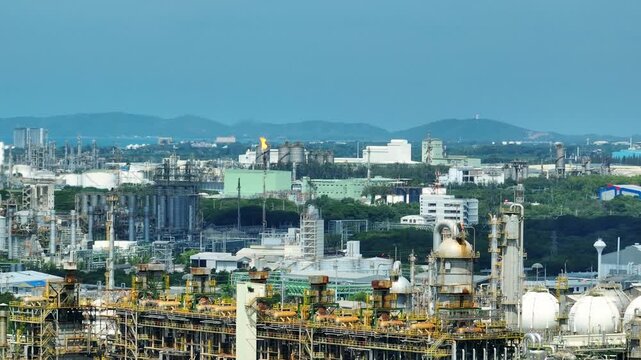 Drone perspective capturing sphere tank storage and complex industrial infrastructure near natural landscapes, representing energy operations and the balance between industry and environmental.
