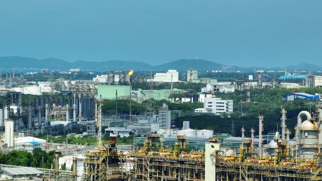 Aerial view of industrial facilities and spherical gas storage tanks surrounded by urban greenery, illustrating industrial nature transition, environmental buffer zones, ESG management challenges.
