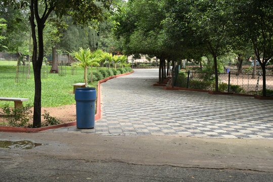 Curved paved walkway through lush green public park with landscaped trees
