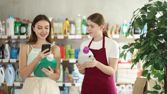Seller offers detergent to the customer while she scans the barcode of the product to read the instructions. European woman scans fabric softener and looks at detailed instructions. High quality 4k