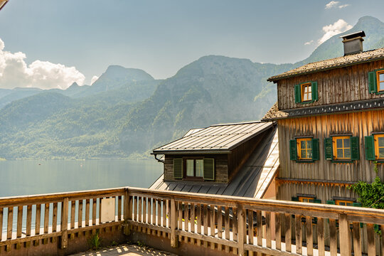 Wooden Alpine House with Green Shutters and Lake Hallstatt with Mountains in Austria