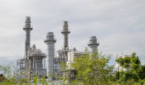 Gas turbine power plant with high exhaust stacks against cloudy sky background, industrial energy generation concept.